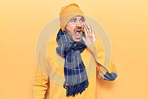 Young handsome bald man wearing winter clothes shouting and screaming loud to side with hand on mouth