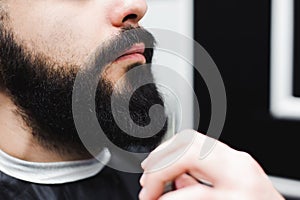 Young handsome barber making haircut of attractive man in barbershop.