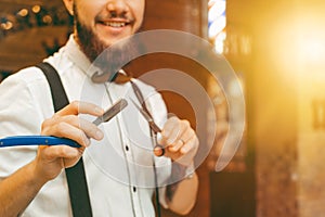 Young handsome bearded barber with scissors and a razor in his hands. Copy space
