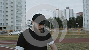 Young handsome bearded caucasian sportsman looking around at running track, checking pulse on smart watch slow motion.