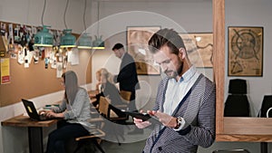 Young handsome bearded man uses touchscreen tablet in the modern startup office.