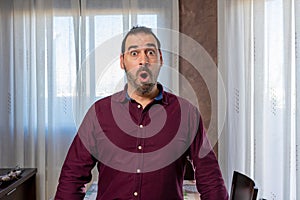 Young handsome bearded man wearing a shirt looking scared and surprised with shocked and astonishing expression