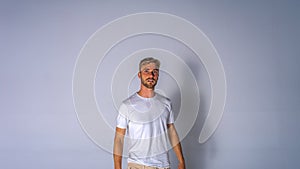 Young handsome blonde man in casual t-shirt on white background isolated,looking straight ahead and serious with mouth open