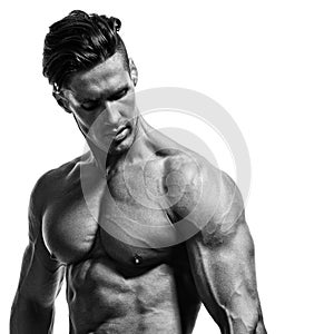 Young handsome bodybuilder shows muscles on the arms, chest and