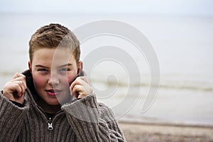 Young handsome boy with pullover at beach in winte