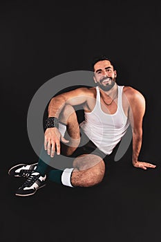 Young handsome break dancer man poses smiling in sportswear sitting on the floor