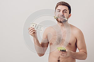 Young handsome brunette man with beard eating hundred dollar bill. money and greed