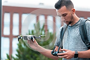 Young Handsome Brunette Man Launching Drone Quadcopter and Looking At Remote Controller Joystick. Urban Stlilysh