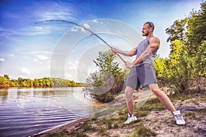 Young handsome brutal caucasian man in casual outfit fishing on