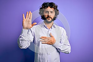 Young handsome business man with beard wearing shirt standing over purple background Swearing with hand on chest and open palm,