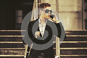 Young handsome business man calling on smartphone on city street