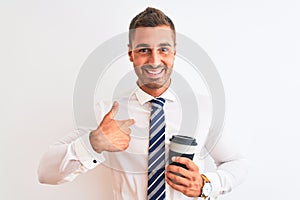 Young handsome business man drinking take away coffee over isolated background with surprise face pointing finger to himself