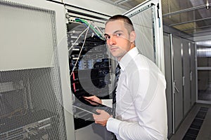 Young handsome business man engeneer in datacenter server room photo