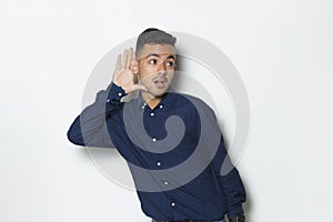 Young handsome business man with hand over ear listening an hearing to gossip isolated on white background