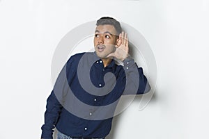 Young handsome business man with hand over ear listening an hearing to gossip isolated on white background