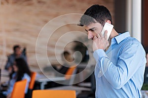 A young, handsome business man at the office building on phone