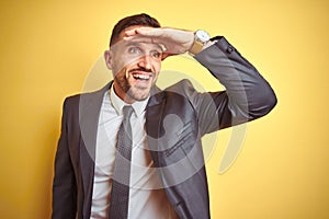 Young handsome business man over yellow isolated background very happy and smiling looking far away with hand over head
