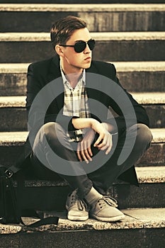 Young handsome business man in sunglasses sitting on steps