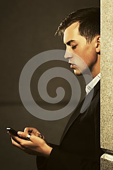 Young handsome business man using cell phone on city street