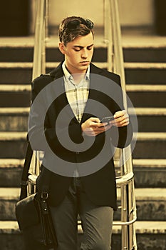 Young handsome business man using cell phone on city street