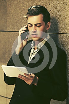 Young handsome business man using tablet computer and calling on cell phone