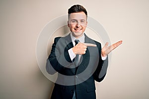 Young handsome business man wearing elegant suit and tie over isolated background amazed and smiling to the camera while