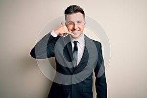 Young handsome business man wearing elegant suit and tie over isolated background smiling doing phone gesture with hand and