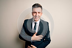 Young handsome business man wearing elegant suit and tie over isolated background smiling and laughing hard out loud because funny