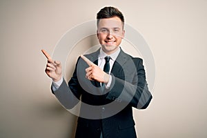 Young handsome business man wearing elegant suit and tie over isolated background smiling and looking at the camera pointing with