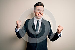 Young handsome business man wearing elegant suit and tie over isolated background very happy and excited doing winner gesture with