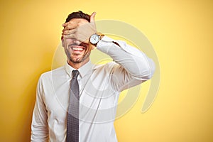 Young handsome business man wearing elegant white shirt over yellow isolated background smiling and laughing with hand on face