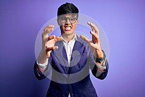 Young handsome business man wearing jacket and glasses over isolated purple background Shouting frustrated with rage, hands trying
