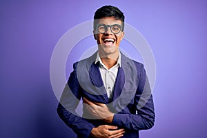 Young handsome business man wearing jacket and glasses over isolated purple background smiling and laughing hard out loud because
