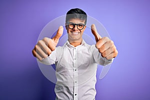 Young handsome business man wearing shirt and glasses over isolated purple background approving doing positive gesture with hand,