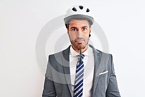 Young handsome business man wearing suit and tie and bike helmet over isolated background with serious expression on face