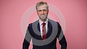 young handsome business man wearing suit and tie on pink background