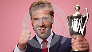 young handsome business man wearing suit and tie on pink background