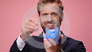 young handsome business man wearing suit and tie on pink background