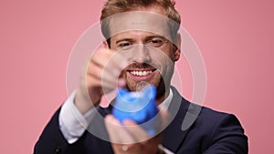 young handsome business man wearing suit and tie on pink background