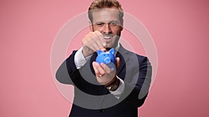 young handsome business man wearing suit and tie on pink background