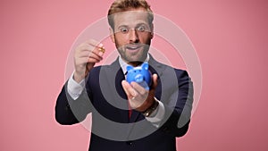 young handsome business man wearing suit and tie on pink background