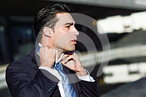 Young handsome businessman adjusting a tie in urban background