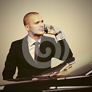 Young handsome businessman calling on phone next to his car