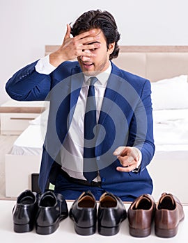 Young handsome businessman choosing shoes at home