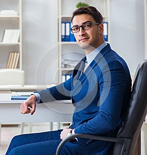 Young handsome businessman employee working in office at desk