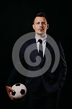 Young handsome businessman holding a football on black background studio.