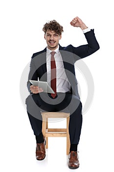 Young handsome businessman holding his tablet and celebrating succes