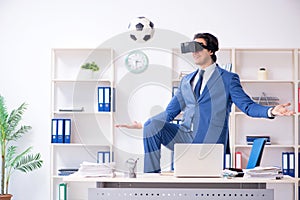 The young handsome businessman playing soccer with virtual glasses