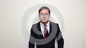 Young handsome businessman puts on glasses and waves his hand in greeting.