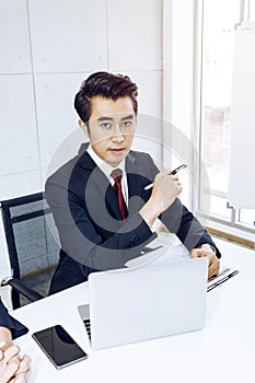 Young handsome businessman smiling and smart with pen and laptop